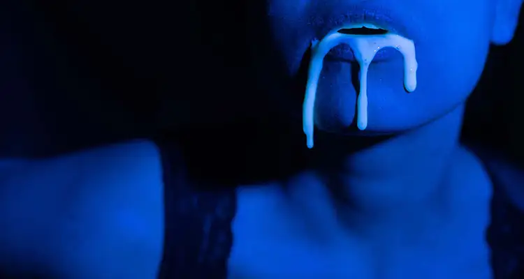 Woman with semen coming out of her mouth. Blue neon lights are shadowing over her