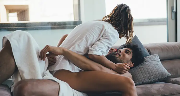 A woman sitting on top of a man, both relaxed on the couch.